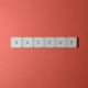 Free Close-up of keyboard keys spelling 'BACKUP' placed on a coral-colored surface. Stock Photo