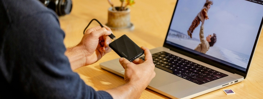 A man sitting at a table with a laptop and cell phone